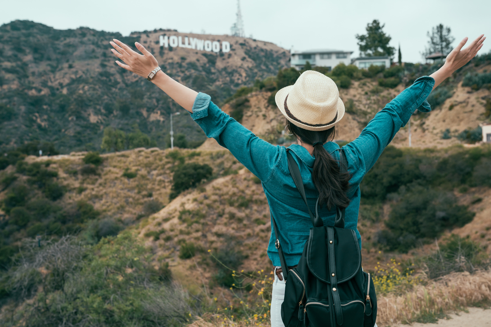 asian woman backpacker love freedom carefree hugging nature while hiking in hollywood hills enjoy fresh air. young girl traveler open arms raising standing on mountain sightseeing view of spring.